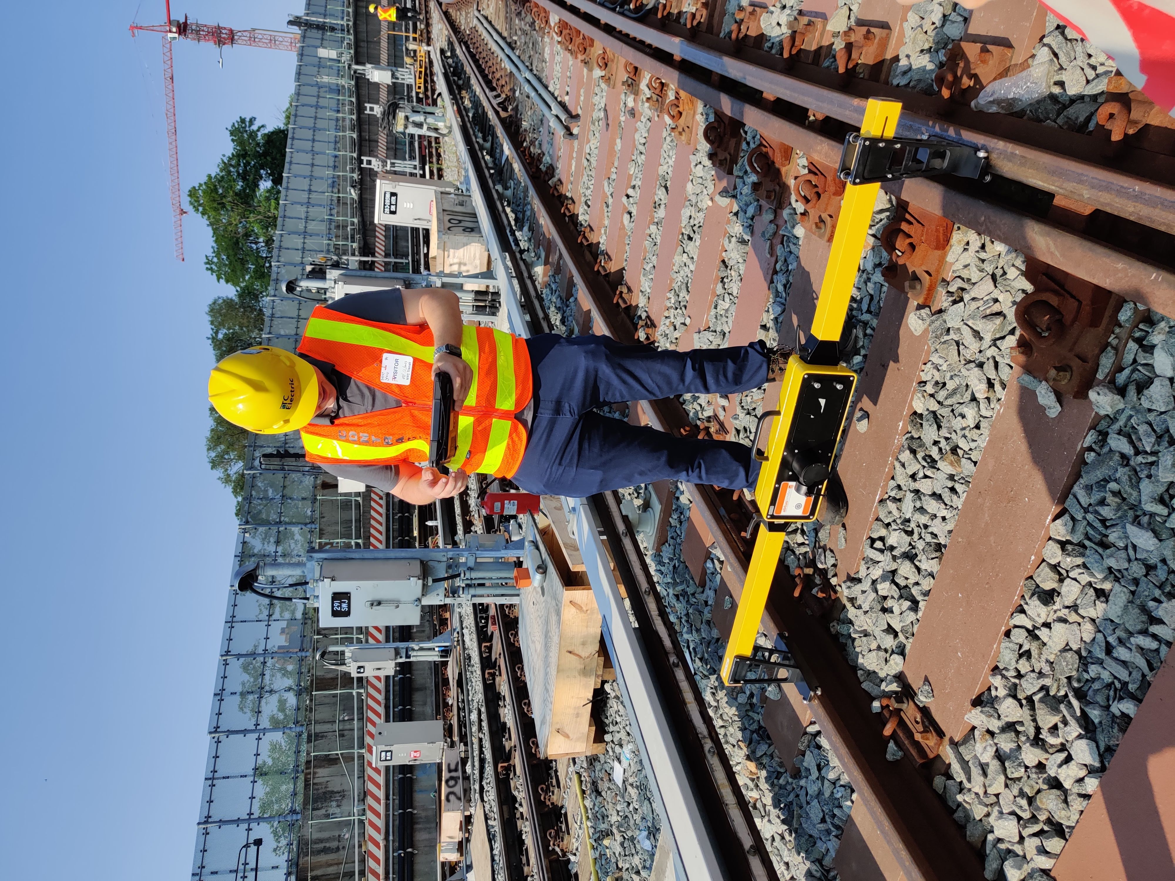 Worker uses a machine sitting on the rails in a railyard.